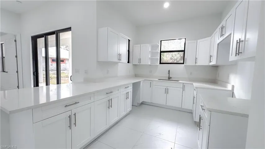 Kitchen with healthy amount of natural light, white cabinetry, and a peninsula