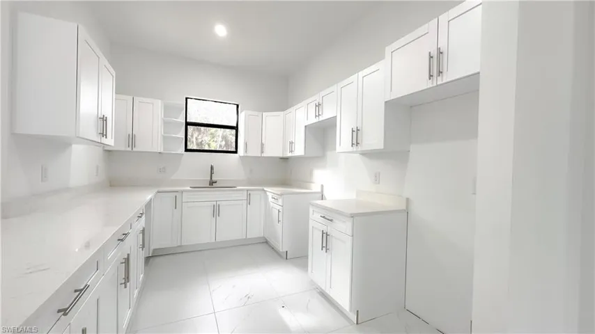 Kitchen featuring light marble finish floors, white cabinets, light stone counters, and recessed lighting