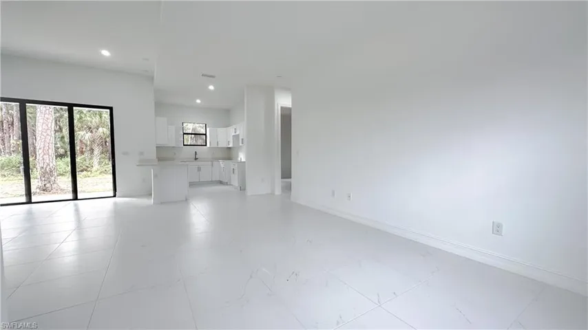 Unfurnished living room featuring recessed lighting and baseboards