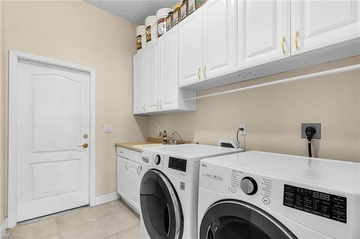 Washroom featuring light tile patterned flooring, independent washer and dryer, and cabinet space