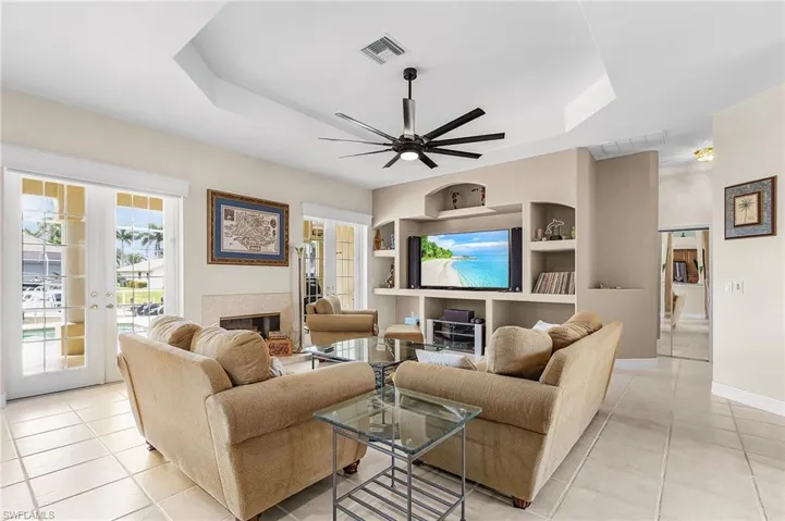 Living area featuring a raised ceiling, french doors, and light tile patterned floors