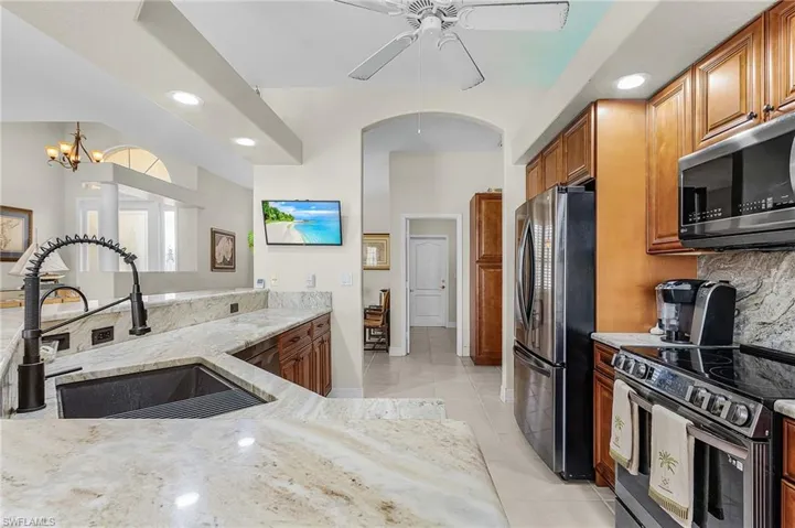 Kitchen with appliances with stainless steel finishes, brown cabinetry, recessed lighting, light stone counters, and tasteful backsplash