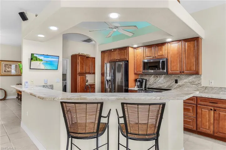 Kitchen with brown cabinets, light tile patterned flooring, tasteful backsplash, and recessed lighting