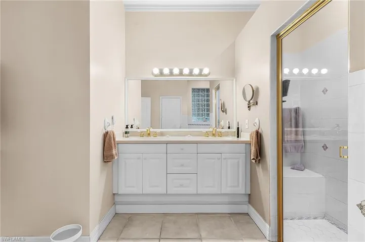 Bathroom featuring a stall shower, double vanity, and light tile patterned flooring