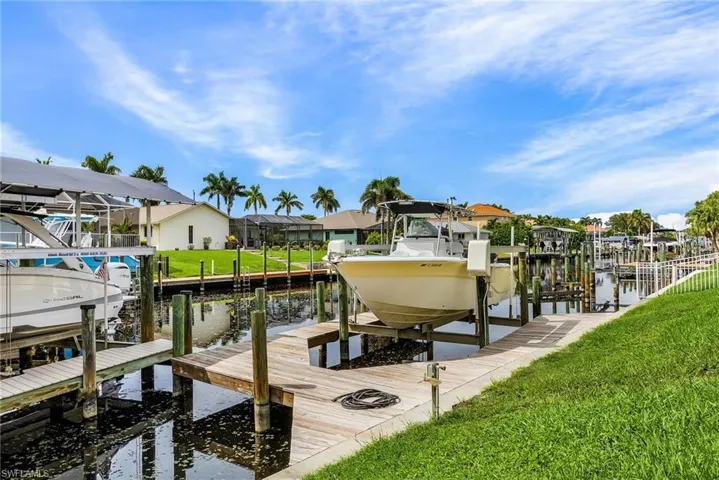 Dock area featuring boat lift, a lawn, a water view, and a residential view