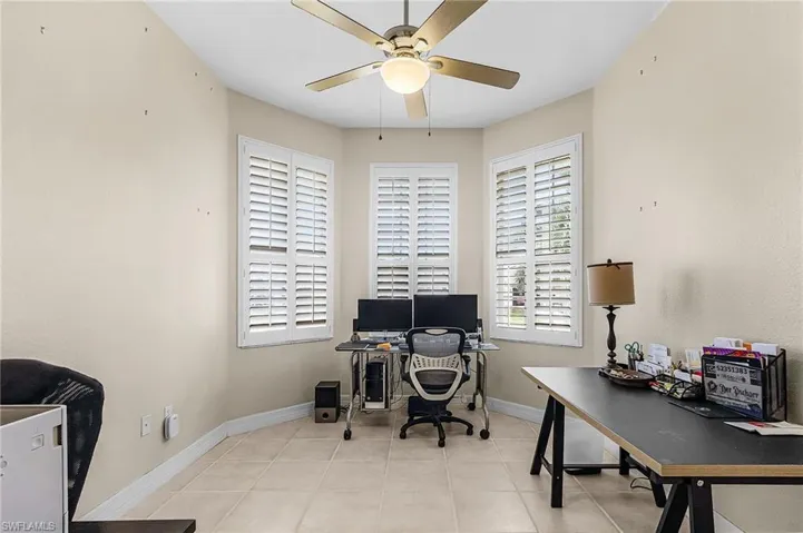 Home office with light tile patterned floors and a ceiling fan