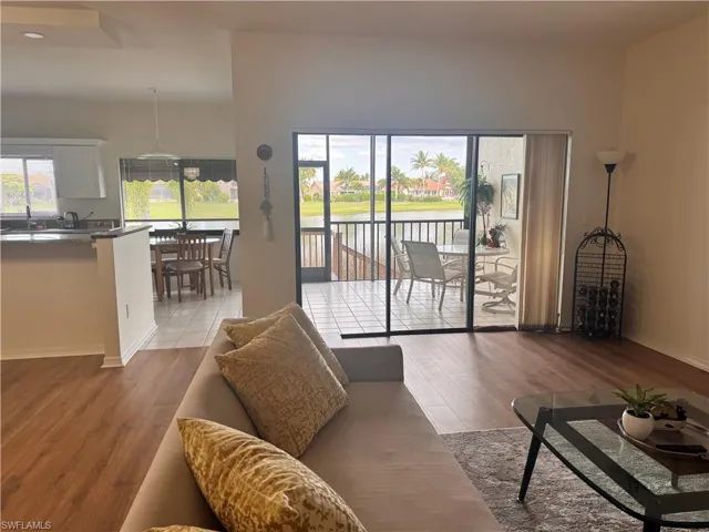 Living area with wood-style flooring and a sliding glass door leading to a screened lanai with tiled flooring