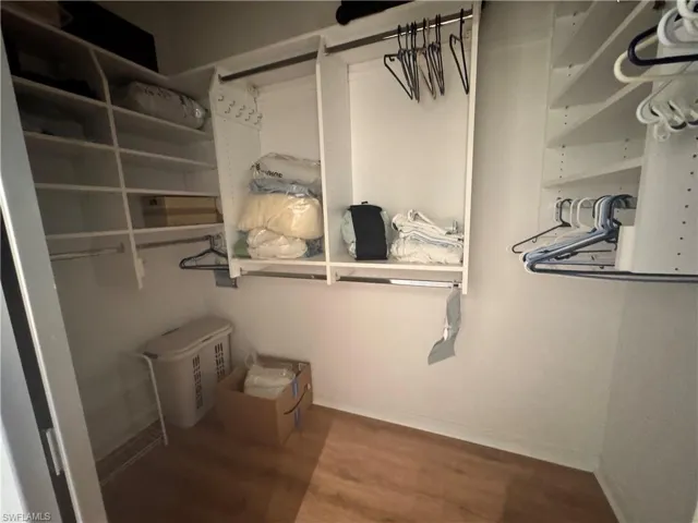 Expansive closet featuring ample shelving, hanging rods, and wood-look flooring