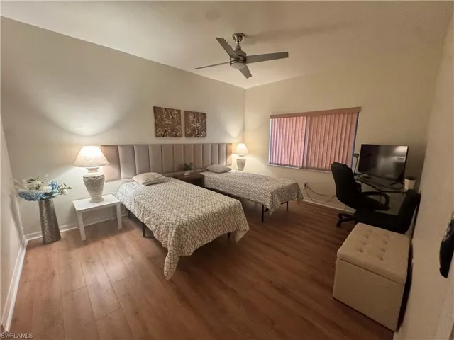 Bedroom featuring wood-finish flooring, a contemporary ceiling fan, and a window with horizontal blinds