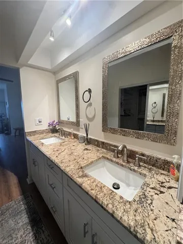 The property features a vanity with dual sinks, granite countertops, and light-colored cabinetry