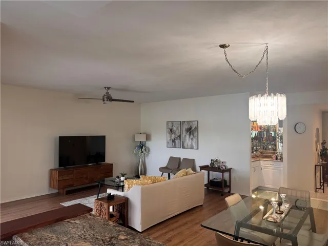 Open concept living and dining area featuring a modern chandelier, a ceiling fan, and wood-look flooring