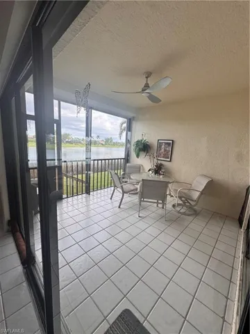 Screened-in patio with light-colored tile flooring, overhead ceiling fan, and sliding glass doors
