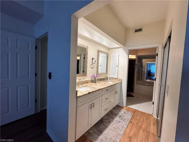 Double vanity featuring light-toned cabinetry, granite countertops, and individual framed mirrors