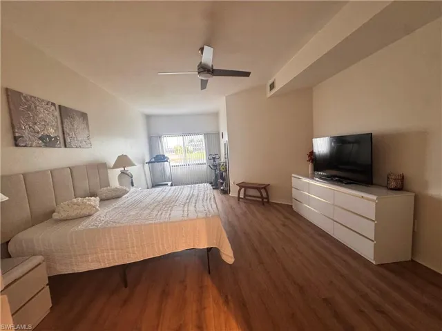 The room features wood-look flooring, a ceiling fan, and a window with horizontal blinds