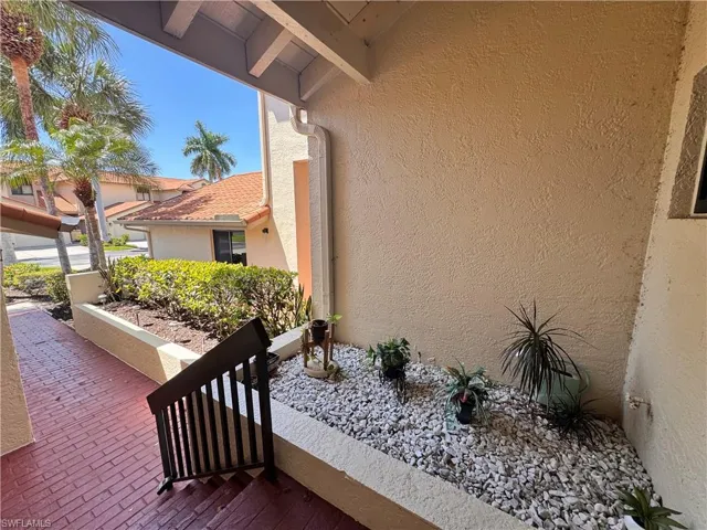 Covered entry with terracotta brick-patterned walkway and dark railing