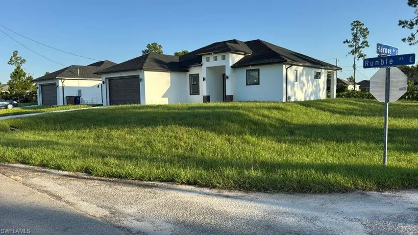 View of front of home featuring stucco siding, a front lawn, and an attached garage