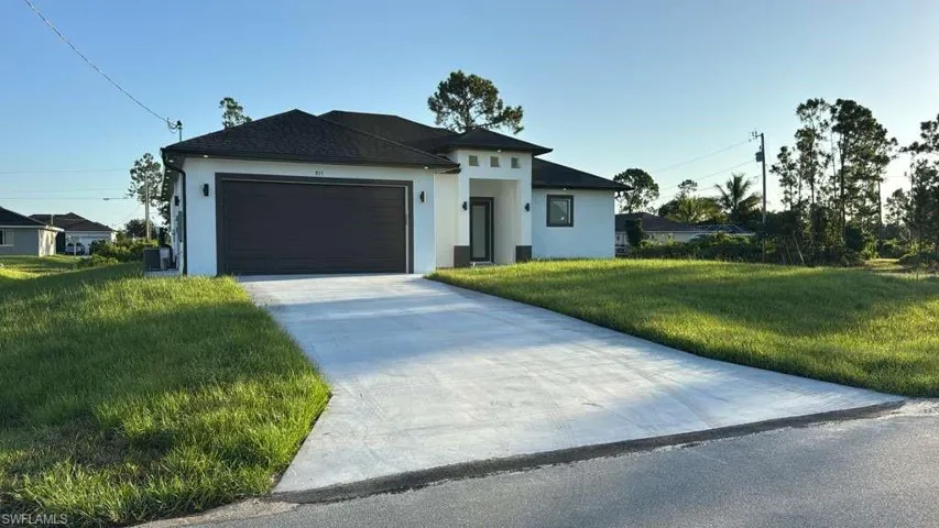 Prairie-style house featuring a garage, stucco siding, driveway, and a front lawn