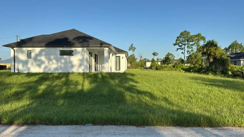 View of side of home featuring stucco siding and a yard