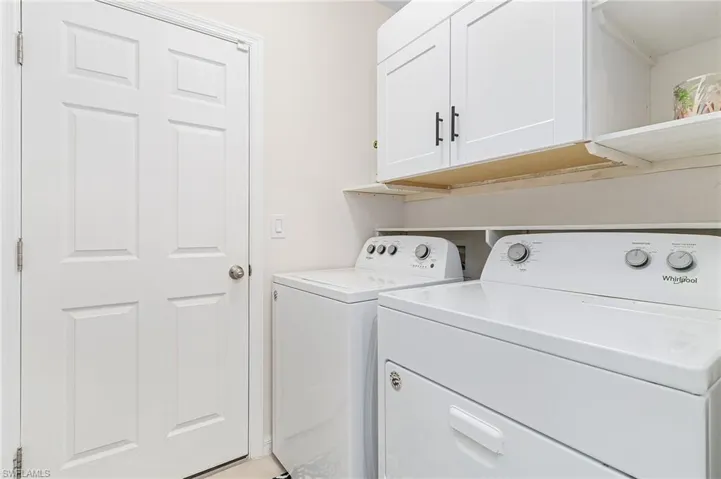 Laundry area featuring separate washer and dryer, cabinets, and washer hookup