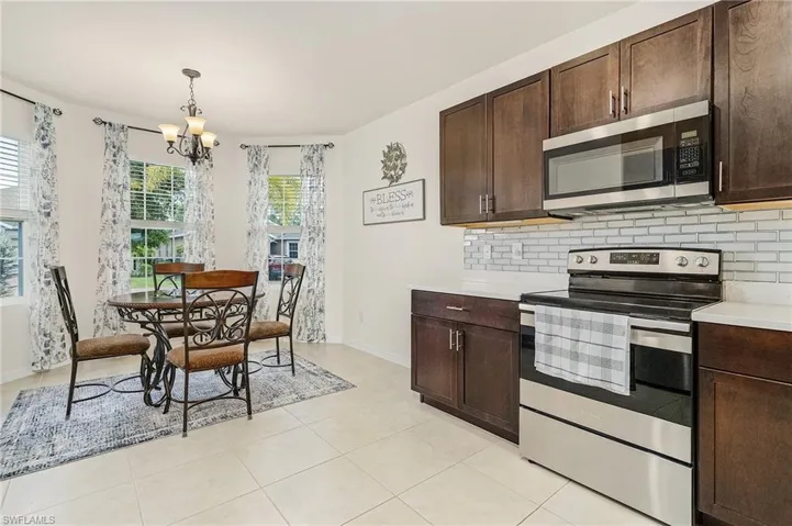 Kitchen with appliances with stainless steel finishes, backsplash, light tile floors, hanging light fixtures, and a chandelier