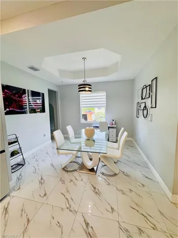 Dining room with a tray ceiling and light marble finish floors