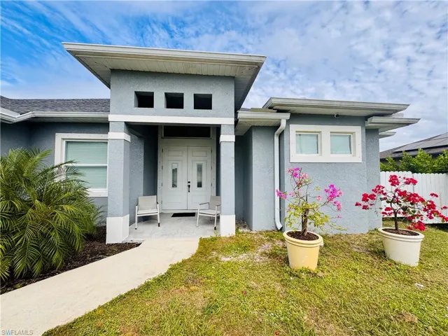 Doorway to property with stucco siding, a yard, and a porch