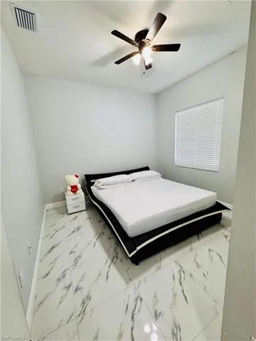 Bedroom featuring light marble finish floors and a ceiling fan