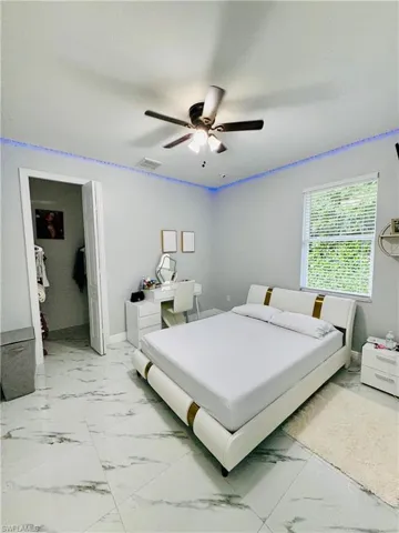 Bedroom with light marble finish floors, a desk, and a ceiling fan