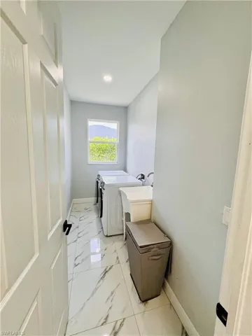 Laundry room featuring separate washer and dryer and light marble finish flooring