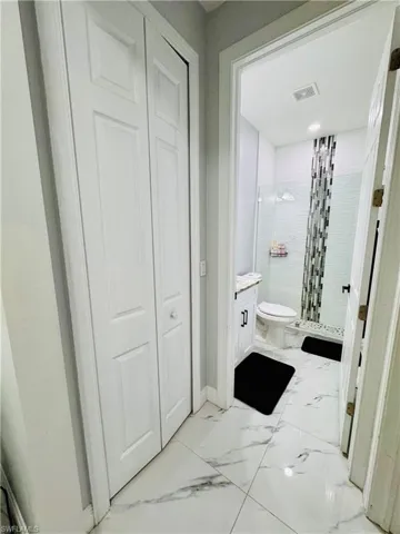 Bathroom with vanity, a stall shower, a closet, and light marble finish floors