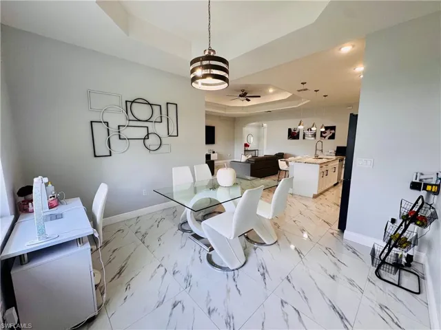 Dining room featuring a tray ceiling, a ceiling fan, arched walkways, and recessed lighting