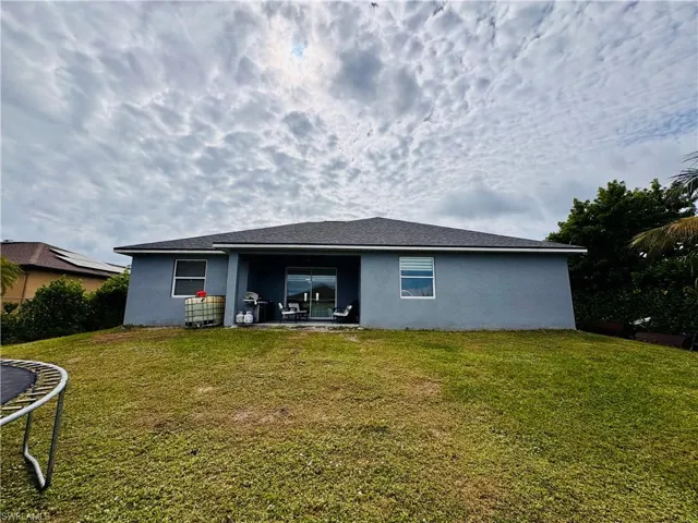 Back of property featuring a patio, stucco siding, a trampoline, and a yard