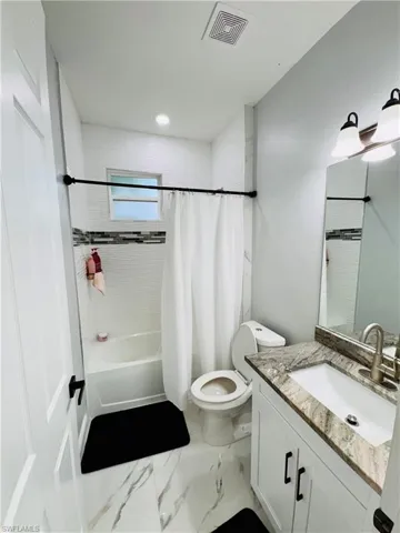 Bathroom with shower / bathtub combination with curtain, vanity, marble look tile flooring, and recessed lighting