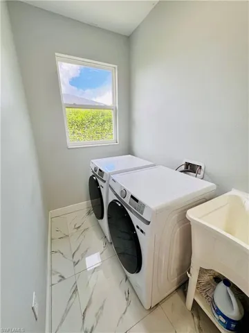 Washroom featuring light marble finish flooring and separate washer and dryer