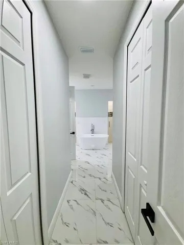 Hall featuring light marble finish floors and a sink
