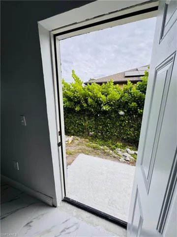 Doorway featuring marble look tile flooring and baseboards