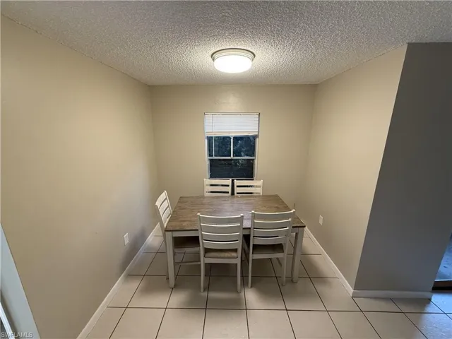 Unfurnished dining area with a textured ceiling and light tile patterned flooring