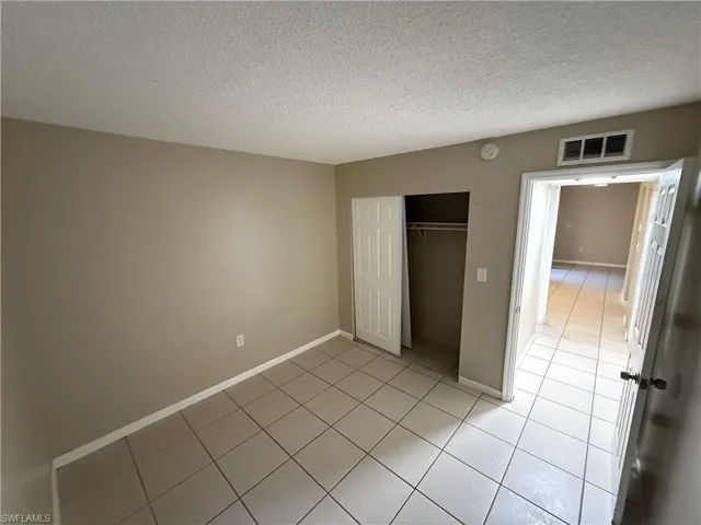 Unfurnished bedroom with a closet, light tile patterned flooring, and a textured ceiling