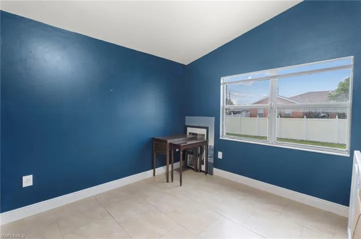 Tiled spare room featuring lofted ceiling