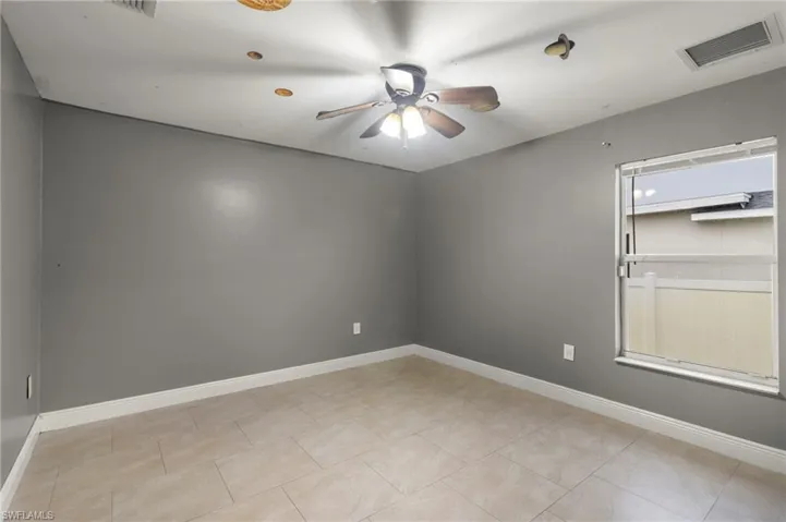 Spare room with ceiling fan and light tile floors