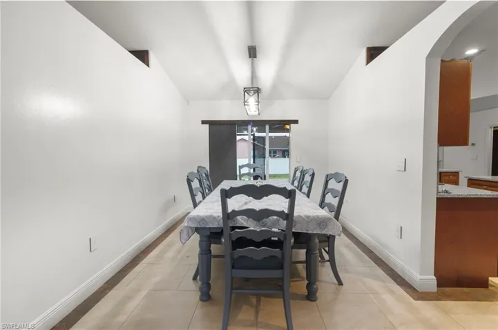 Dining area featuring vaulted ceiling and light tile floors