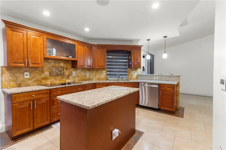 Kitchen featuring a kitchen island, black electric cooktop, decorative light fixtures, dishwasher, and light tile floors