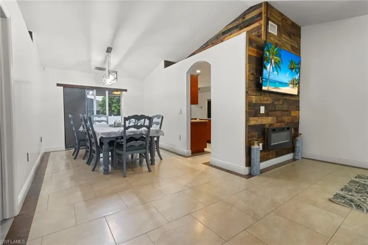 Tiled dining space with a stone fireplace and vaulted ceiling