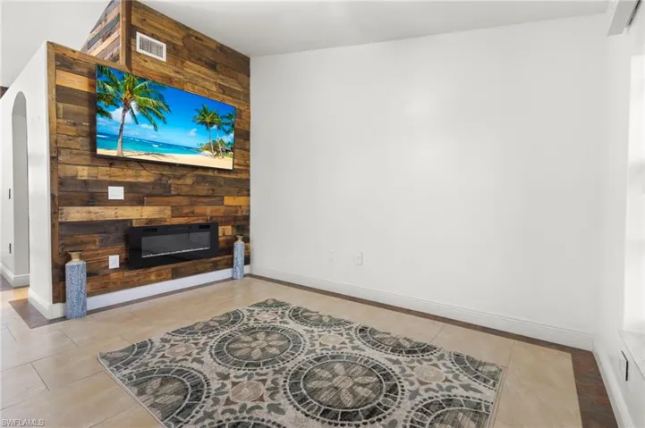 Living room with light tile floors, wood walls, and a fireplace