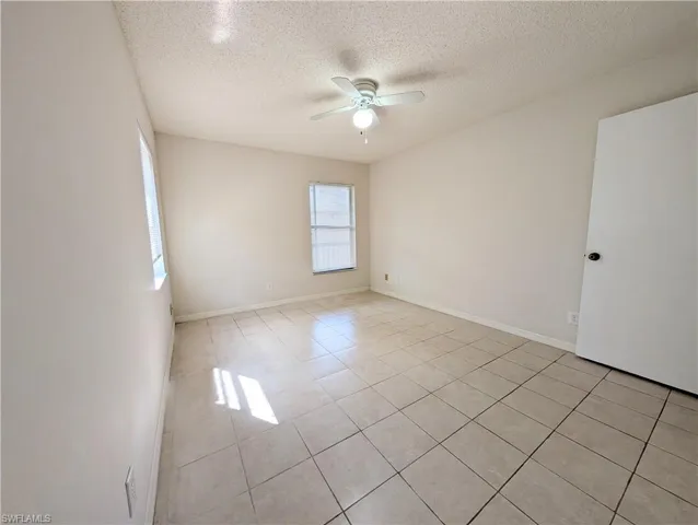 Unfurnished room featuring a textured ceiling, light tile patterned floors, and a ceiling fan
