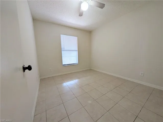 Unfurnished room with light tile patterned flooring, a textured ceiling, and ceiling fan