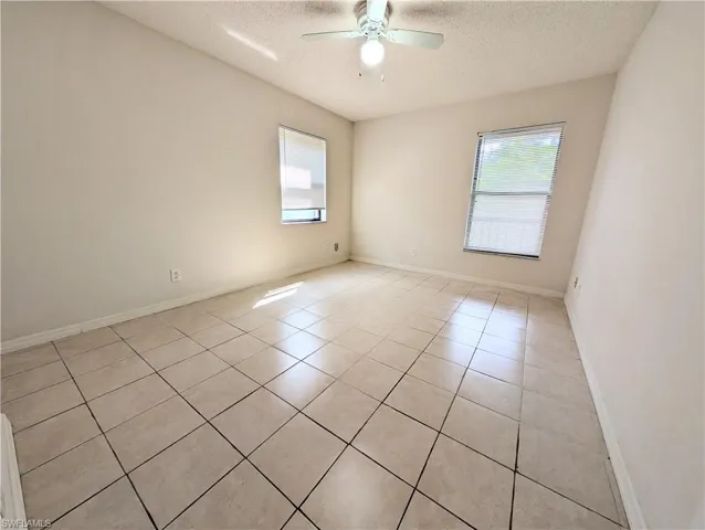 Spare room with light tile patterned flooring, a textured ceiling, and ceiling fan