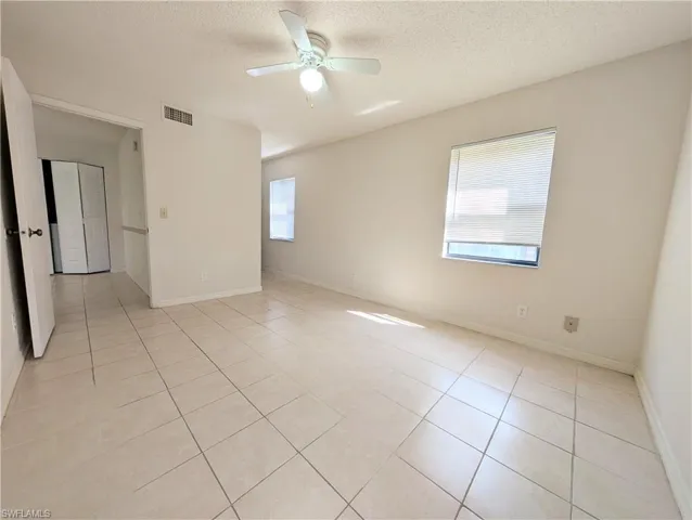 Spare room with light tile patterned flooring, a textured ceiling, plenty of natural light, and ceiling fan