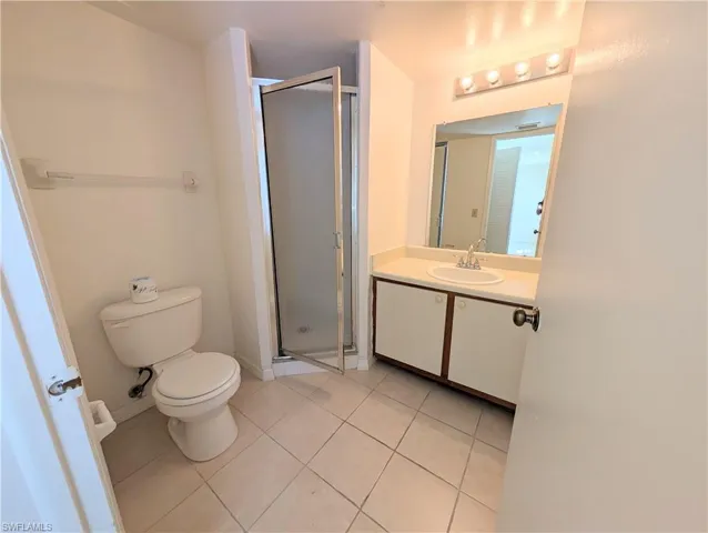 Full bathroom with a stall shower, vanity, and light tile patterned flooring