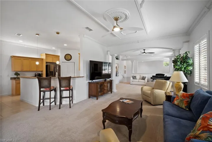 Living room with ornate columns, ceiling fan, and ornamental molding